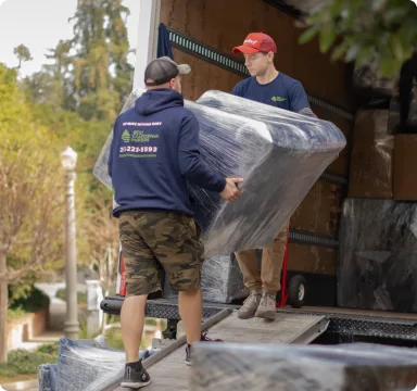 Movers loading a wrapped sofa into the truck