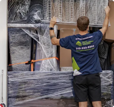 Mover wrapping furniture in protective plastic before loading