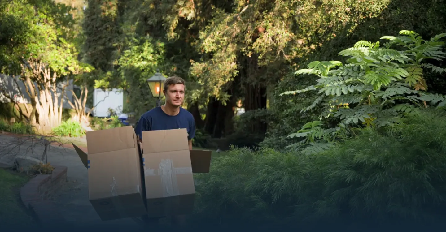 Mover carrying packed boxes along a garden path
