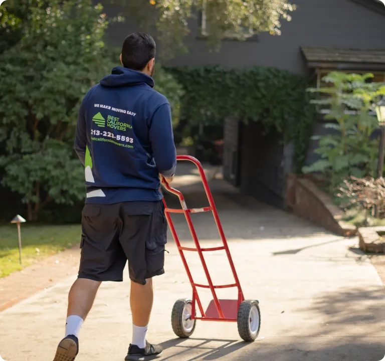 Mover wheeling a hand truck up a driveway