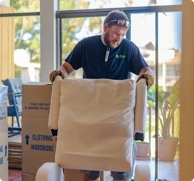 Mover carrying a wardrobe box into a home